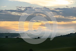 Sunrise or sunset over the hills and meadow.