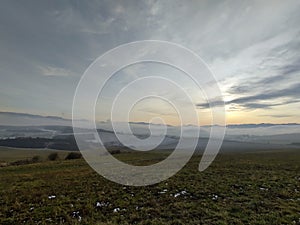 Sunrise or sunset over the hills and meadow.