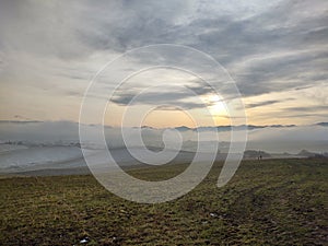 Sunrise or sunset over the hills and meadow.