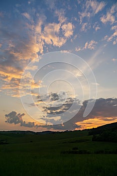 Sunrise or sunset over the hills and meadow.