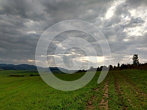 Východ nebo západ slunce nad kopci a loukou.