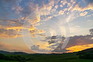 Sunrise or sunset over the hills and meadow.