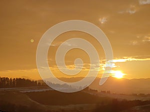 Sunrise or sunset over the hills and meadow.