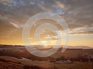 Sunrise or sunset over the hills and meadow.