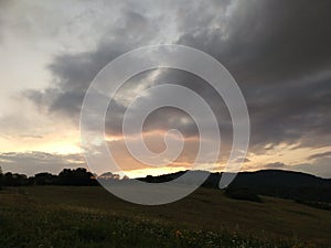 Sunrise or sunset over the hills and meadow.