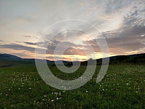 Sunrise or sunset over the hills and meadow.