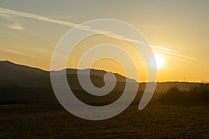 Sunrise or sunset over the hills and meadow.