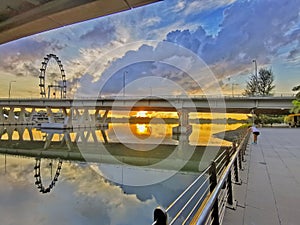 Sunrise or sunset with sky reflection on water and ferris wheel in background