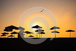 Sunrise with sunshade and life guard station silhouette