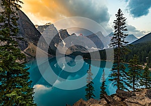 Sunrise with turquoise waters of the Moraine lake with sin lit rocky mountains in Banff National Park of Canada in