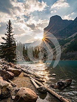 Sunrise with turquoise waters of the Moraine lake with sin lit rocky mountains in Banff National Park of Canada in