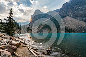 Sunrise with turquoise waters of the Moraine lake with sin lit rocky mountains in Banff National Park of Canada in