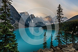Sunrise with turquoise waters of the Moraine lake with sin lit rocky mountains in Banff National Park of Canada in