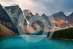 Sunrise with turquoise waters of the Moraine lake with sin lit rocky mountains in Banff National Park of Canada in