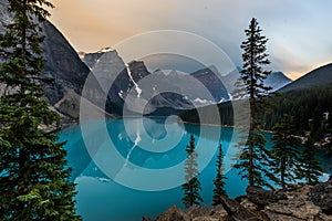 Sunrise with turquoise waters of the Moraine lake with sin lit rocky mountains in Banff National Park of Canada in