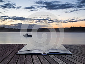 Sunrise vibrant landscape of boat on calm lake conceptual book i