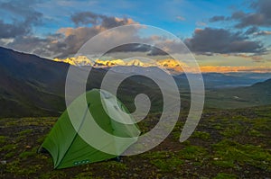 Sunrise view of Mount Denali - mt Mckinley peak with alpenglow during golden hour with green camping tent in the