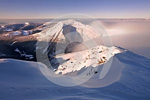 Sunrise view of Pec pod Snezkou in the Krkonose Mountains in winter. Czech Republic. Morning panoramic view above clouds.