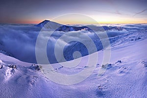 Sunrise view of Pec pod Snezkou in the Krkonose Mountains in winter. Czech Republic. Morning panoramic view above clouds.