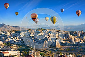 Colorful hot air balloons fly in blue sky over amazing rocky valley in Cappadocia, Turkey