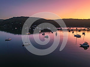 Sunrise waterscape over the bay nestled at the foot of the mountains with boats and a clear sky