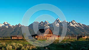 Sunrise wide shot of a mormon row barn and grand teton mountain