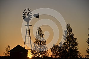 Sunrise with windmill and barn silhouette