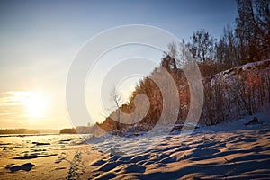 Sunrise on winter morning and trees with bare branches on a cold sunny time and snow on field