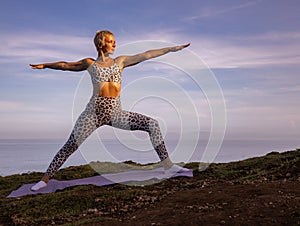 Sunrise yoga. Caucasian woman practicing Virabhadrasana II, Warrior II Pose. Strong body. Healthy lifestyle. Self-care concept.