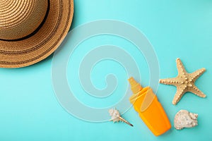 Sunscreen bottle with hat and shells on blue background. Cosmetics for safe sunburn. Top view, flatlay. Sun protection cream with