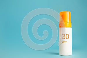 Sunscreen bottle with spf 30 cream or lotion on the aqua blue background with copy space. Sun protection, sunblock, uv cosmetic