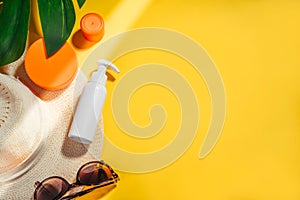 Sunscreen. Hat with sunglasses and protection cream spf Flat lay on yellow background. Beach accessories. Summer Concept