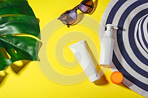 Sunscreen. Hat with sunglasses and protection cream spf Flat lay on yellow background. Beach accessories. Summer Concept