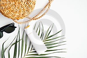 Sunscreen lotion cream bottle with tropical palm leaf and beach accessories on white background. Summer holiday vacation, sun
