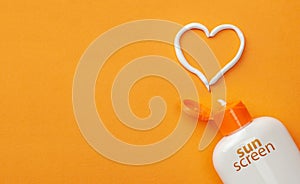 Sunscreen on orange background. Plastic bottle of sun protection and white heart-shaped cream