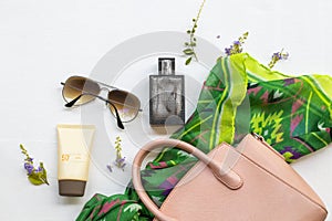 Sunscreen spf50, perfume, green scarf, sunglasses and pink hand bag accessories of lifestyle woman