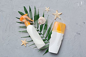 Sunscreen spray bottle. Bottle with sun protection cream and sea shells with tropical green leaf on color background