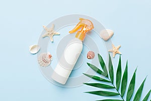 Sunscreen spray bottle. Bottle with sun protection cream and sea shells with tropical green leaf on color background