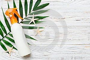 Sunscreen spray bottle. Bottle with sun protection cream and sea shells with tropical green leaf on color background