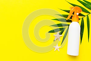 Sunscreen spray bottle. Bottle with sun protection cream and sea shells with tropical green leaf on color background