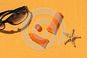 Sunscreen, starfish and sunglasses on a sandy background