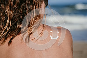 Sunscreen sun drawing lotion on suntan back relaxing tanning at the beach. Woman sitting and relaxing with a smiling shape face