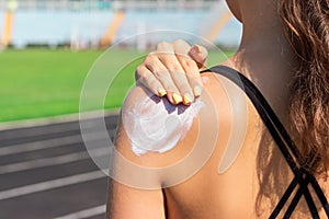 Sunscreen sunblock. Woman in a sportswear putting solar cream on shoulder on beautiful summer day. Sporty woman applying sunscreen