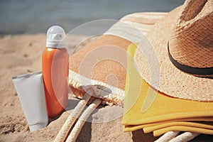 Sunscreens, straw hat, bag and towel on beach, closeup. Sun protection care