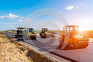 Sunset above the road roller working on the construction site