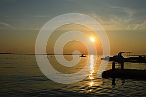 Sunset above Vrsi Mulo beach in Croatia, Adriatic sea with silhouettes of small boats, buoys and molo visible. photo