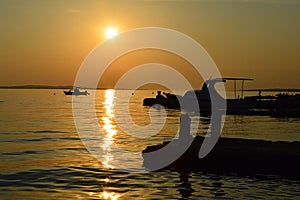 Sunset above Vrsi Mulo beach in Croatia, Adriatic with silhouette of boats and molos photo