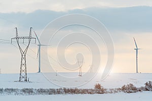 Sunset above windmill and powerlines on the field in winter