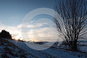 Sunset above winter snowy road and countryside with agricultural fields under Low Tatras mountains.