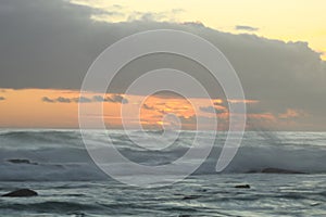 Sunset across rough seas and cloudy skies